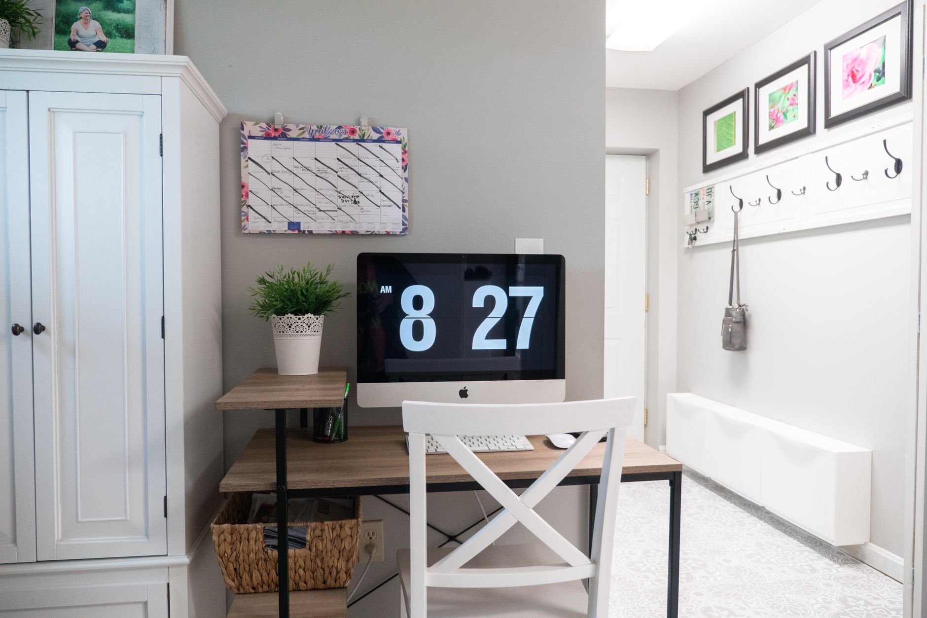 A stylish home office featuring a minimalist desk setup with a large screen and decorative elements.