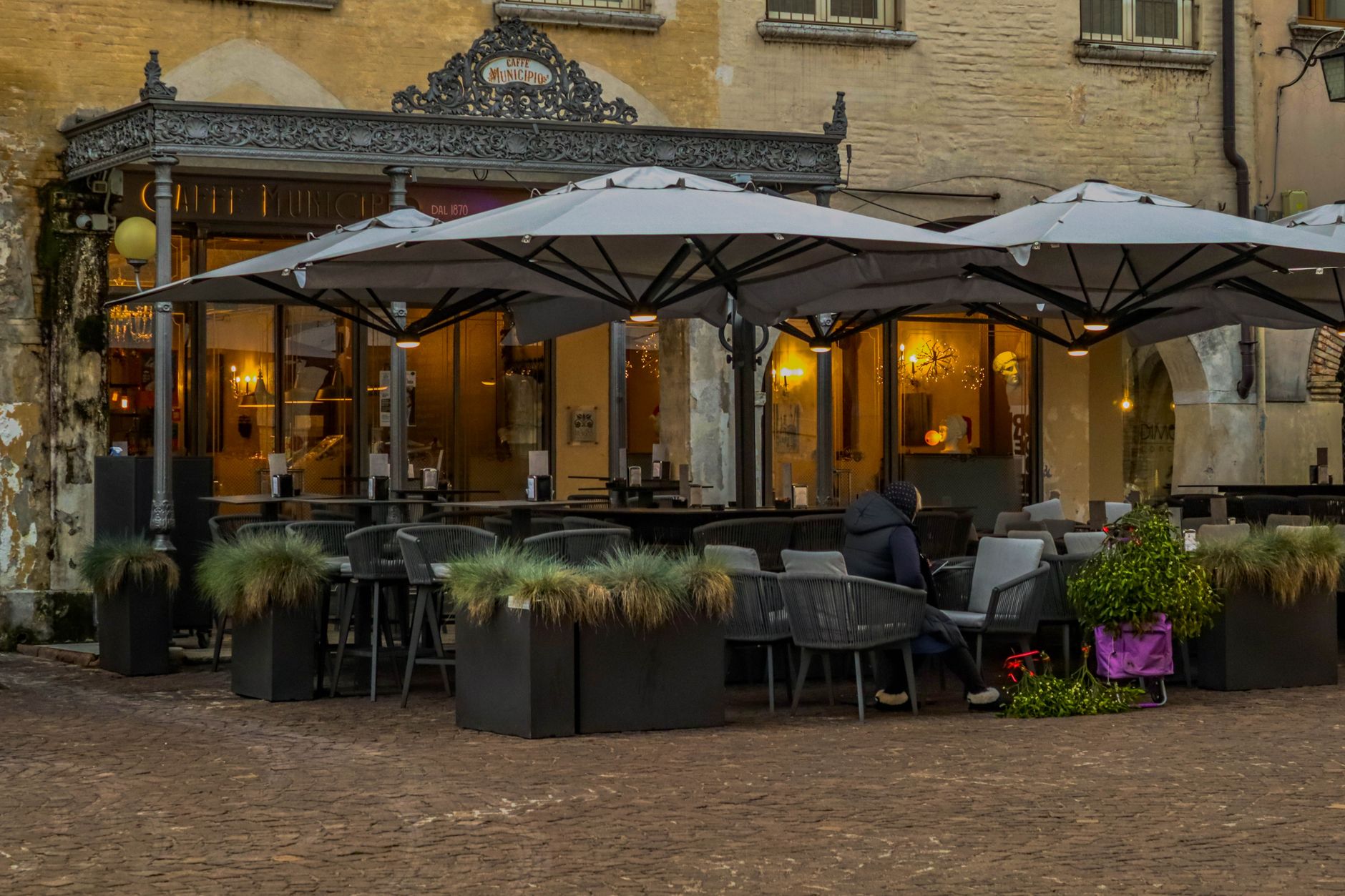 Charming European café exterior with cozy seating and large umbrellas.