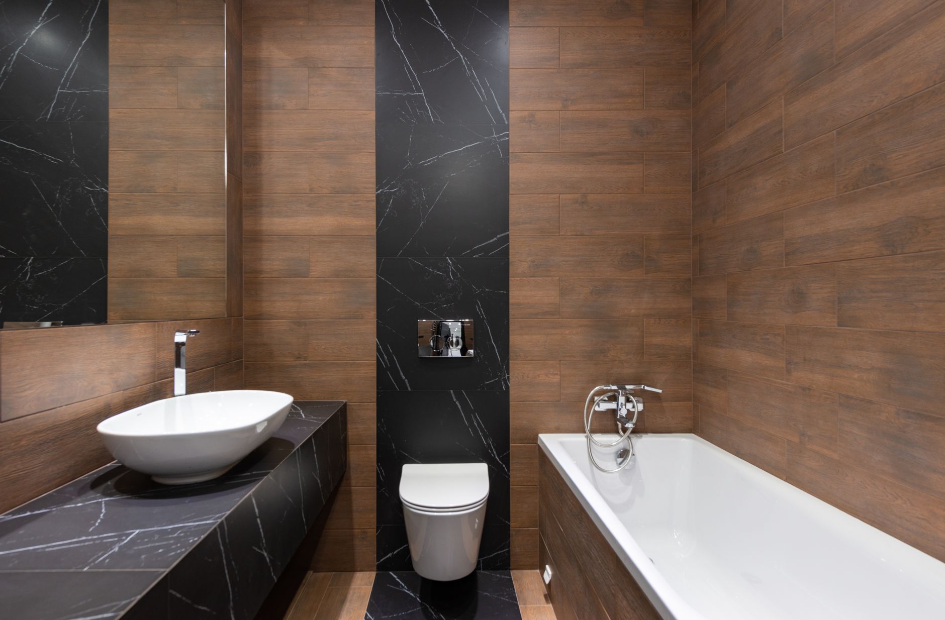 Sleek modern bathroom featuring wood paneling and marble accents, with a white basin and bathtub.